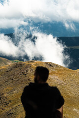 Persona an&oacute;nima sentada mirando monta&ntilde;as con nubes