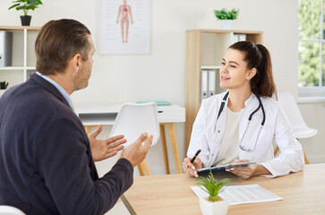 Smiling female doctor or nurse is talking to a patient during a consultation in the hospital. The...