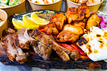 Grilled meats with fresh lemon and vegetables served on a wooden platter