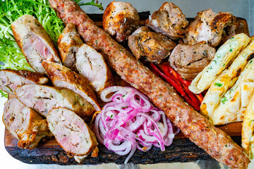 Delicious variety of grilled meats served on wooden platter with sides