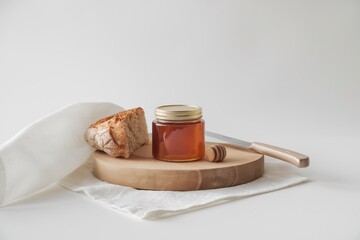 Honey jar bread and knife on wooden board