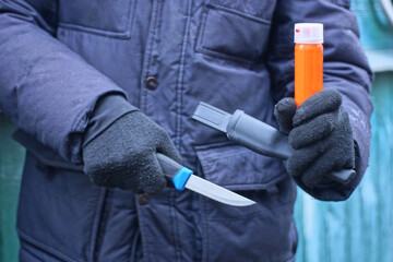 one aggressive male criminal in black clothes holds a knife and an orange gas canister in his hands...