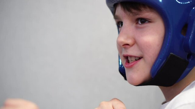 boy in taekwondo helmet grins evilly close-up portrait