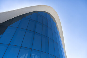 Modern glass curved building against deep blue sky