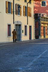 Obraz premium Cobblestone street, old buildings, and a passerby.