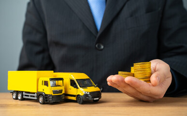 Businessman holds stacks of coins in outstretched hand and truck with delivery van. Profit from the transport company, industry. Profitability of courier deliveries and transportation.