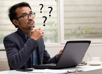 Businessman thinking and question mark ,what, why, reason, problem while working at  workplace 