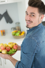 Obraz premium young man holding a bowl of fruits