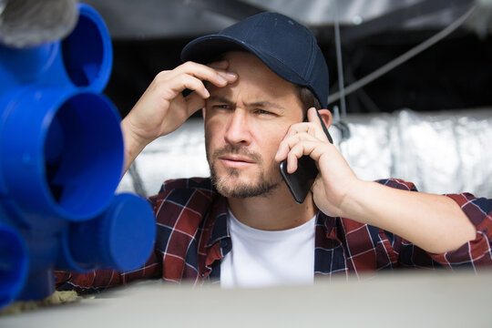 young contractor receiving telephone call while working in roofspace