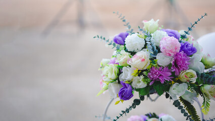 A vibrant floral arrangement featuring pink, purple, and white flowers, beautifully presented with greenery in a soft-focus background.
