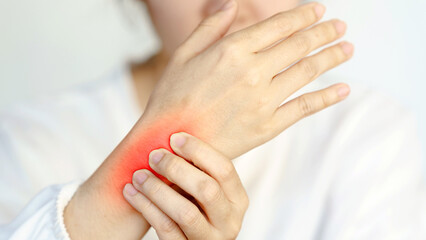 A person experiencing wrist pain, shown gripping their wrist with a red area indicating discomfort.