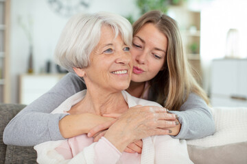adult granddaughter giving her grandmother a kiss