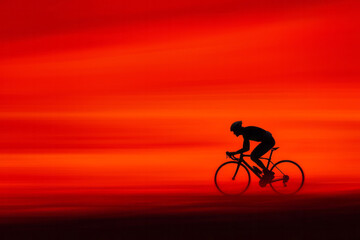 A cyclist&acirc;&euro;&trade;s silhouette riding against the backdrop of a dramatic sunset, symbolizing strength and perseverance,