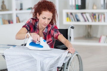 woman on wheelchair during ironing at home