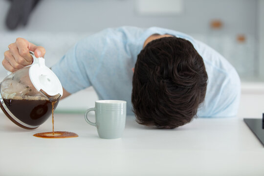 sleepy man pouring coffee next to cup at home