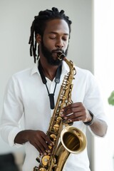 Fototapeta premium A man with dreadlocks is playing a saxophone. The saxophone is gold and the man is wearing a white shirt