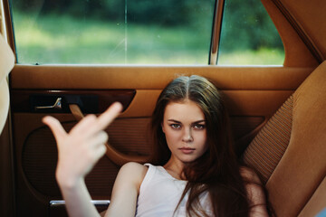 Defiant young woman in a car showing a rebellious attitude, showcasing confidence and strength with...