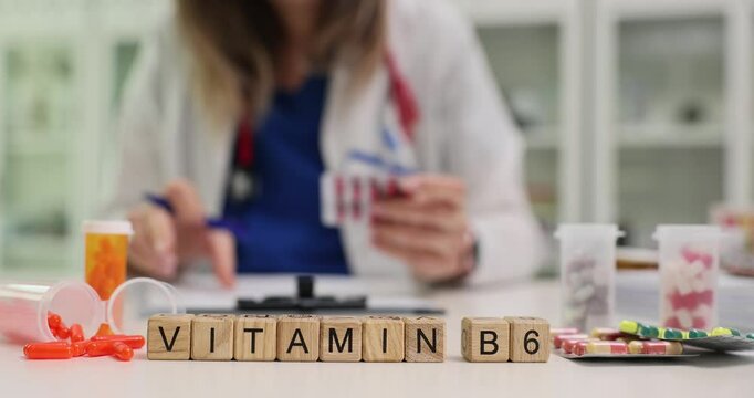 Text Vitamin B6 with blocks and capsules at female pharmacist workplace. Preparing supplements for recovery and wellbeing in hospital slow motion