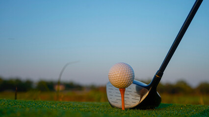 Golf clubs and balls on a green lawn in a beautiful golf course with morning sunshine.