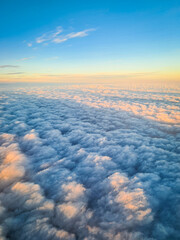 A tranquil aerial view of a vast sea of clouds illuminated by soft golden and pastel hues on the horizon. The scene captures the beauty of nature from above