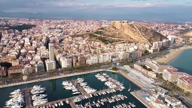 Cinematic aerial view of Alicante city. Famous travel destination in Spain. View of Castle of Santa B&aacute;rbara on top of the hill. Sunset point with orange and pink reflections. Promenade of Alicante.