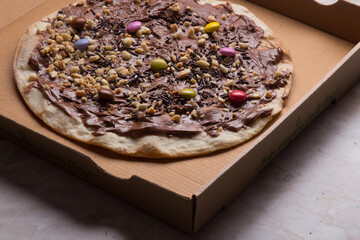Pizza na caixa de papelão com queijo mozarela e vários sabores e condimentos, feita de massa fina, farinha