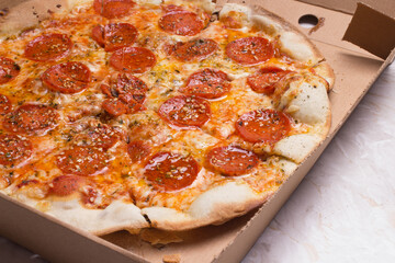 Pizza na caixa de papelão com queijo mozarela e vários sabores e condimentos, feita de massa fina, farinha
