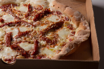 Pizza na caixa de papel&atilde;o com queijo mozarela e v&aacute;rios sabores e condimentos, feita de massa fina, farinha