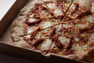 Pizza na caixa de papel&atilde;o com queijo mozarela e v&aacute;rios sabores e condimentos, feita de massa fina, farinha