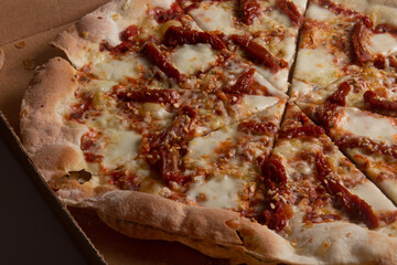 Pizza na caixa de papel&atilde;o com queijo mozarela e v&aacute;rios sabores e condimentos, feita de massa fina, farinha