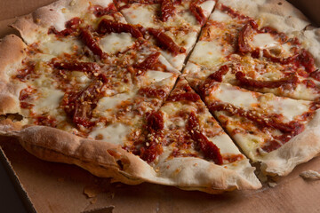 Pizza na caixa de papel&atilde;o com queijo mozarela e v&aacute;rios sabores e condimentos, feita de massa fina, farinha