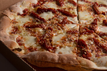 Pizza na caixa de papel&atilde;o com queijo mozarela e v&aacute;rios sabores e condimentos, feita de massa fina, farinha