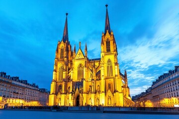 Obraz premium A stunning Gothic cathedral illuminated at dusk, showcasing intricate architecture and towering spires against a vibrant evening sky.