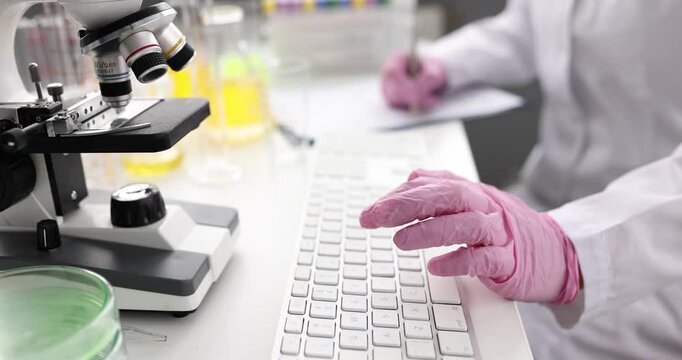 A dedicated scientist in a lab coat uses a microscope and keyboard, exploring various aspects of research