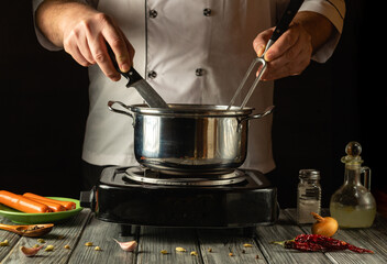 An experienced cook expertly maneuvers a knife and fork while stirring the contents of a pot on the...