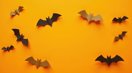 Naklejka premium A festive arrangement of dark and light brown paper bats on an autumnal orange background provides ample space for text or design elements.