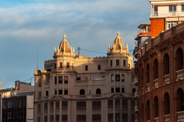 Obraz premium Sunlight casting golden glow on modernist architecture with domed towers near valencia bullring, highlighting contrasting architectural styles during sunset hour