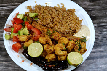 Mixed seafood of fried Saurida undosquamis, the brushtooth lizardfish, large-scale grinner or largescale saury, fried shrimps, Tahini, green salad, pickled eggplant, red fish rice and lemon