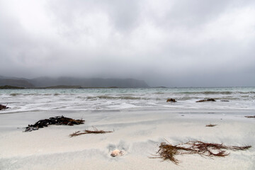 Low angle view over the sand of Ramberg Beach, Ramberg, Norway on the Lofoten island chain archipelago with mountains covered in heavy clouds in the background