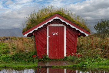 Close up of a wooden public toilet (WC) in shape of a traditional (fisherman) cabin (rorbu) with sod roof on the Lofoten island chain archipelago 