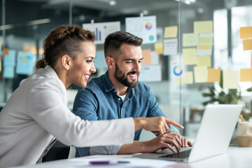 Enthusiastic colleagues collaborating on a laptop in a modern office setting.