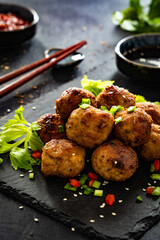 Fried meatballs in asian style on stone board on black background	