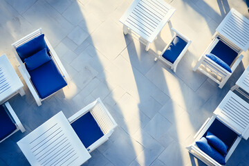 A luxurious outdoor lounge area featuring stylish white furniture, turquoise accents, and a panoramic ocean view under a bright blue sky with fluffy clouds.