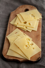 Slices of Maasdam cheese on a wooden board, side view.