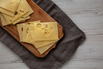 Slices of Maasdam cheese on a wooden board, top view. Close-up.