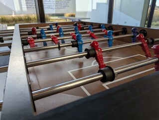 A close portrait of a foosball table at the level of the minature plastic soccer or football players in a bar or café. they are ready to be played with.