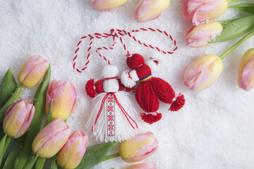 Martenitsa, Martisor, on snow framed with pink tulips