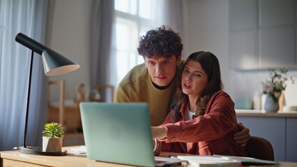 Embracing spouses looking laptop in kitchen enjoying morning together closeup