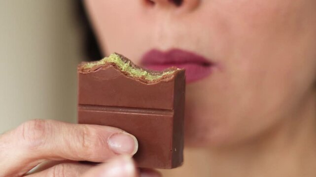 Close up of woman portrait eating Dubai chocolate with green pistachio paste, cream and kataifi dough isolated on white background. Trend dessert. Banner	