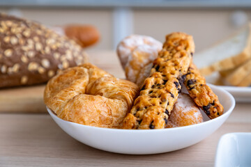 Fresh pastries and bread in a white bowl for breakfast